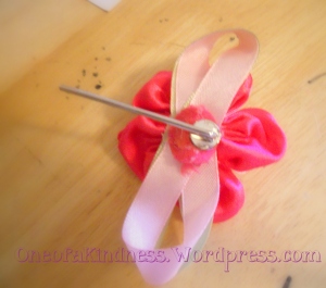 Next, I squeezed a dab of hot glue onto the pin's disk & stuck the felt back of the flower onto it.  While it cooled, I pulled at the stringy bits & overflow, then rolled them around in a rubbery ball.  Because I like to do that with hot glue.